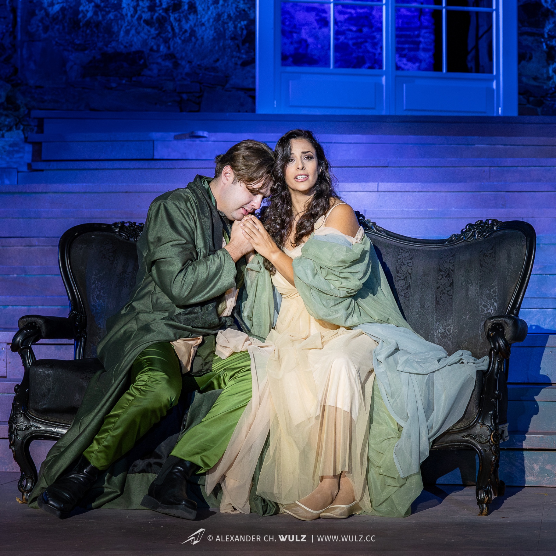Hila Fahima as Violetta in La traviata, Oper Burg Gars 2025 — on the sofa with Alfredo kissing her hand, photo by Alexander Wulz
