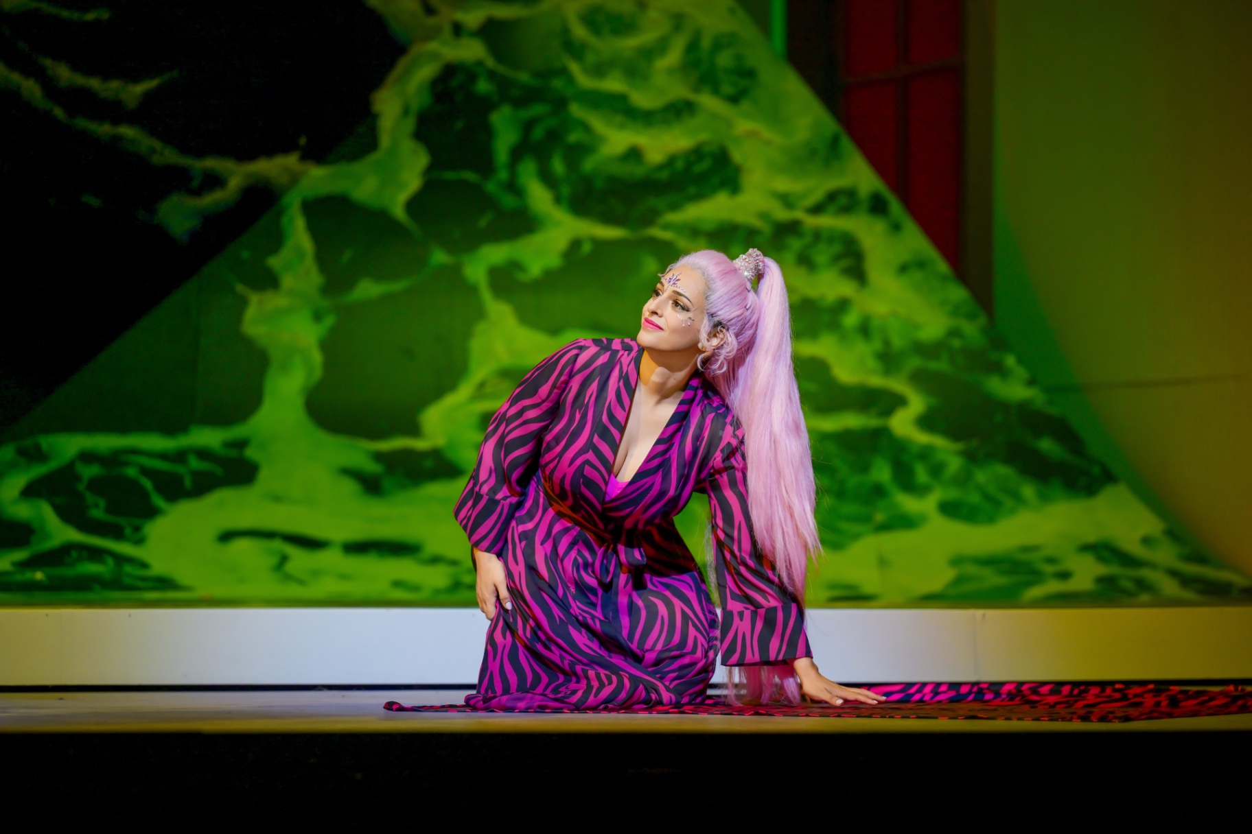 Hila Fahima, Zerbinetta in Ariadne auf Naxos, Tel Aviv Opera 2025 — kneeling in a pink zebra-print robe, photo by Aviad Tevel