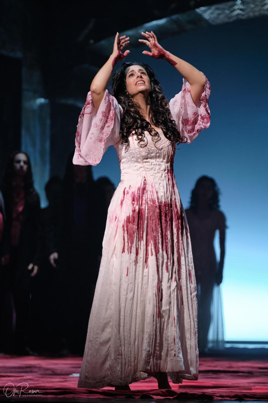 Hila Fahima in the title role of Lucia di Lammermoor, Tel Aviv 2024 — arms raised in the mad scene, photo by Ofer Rosner