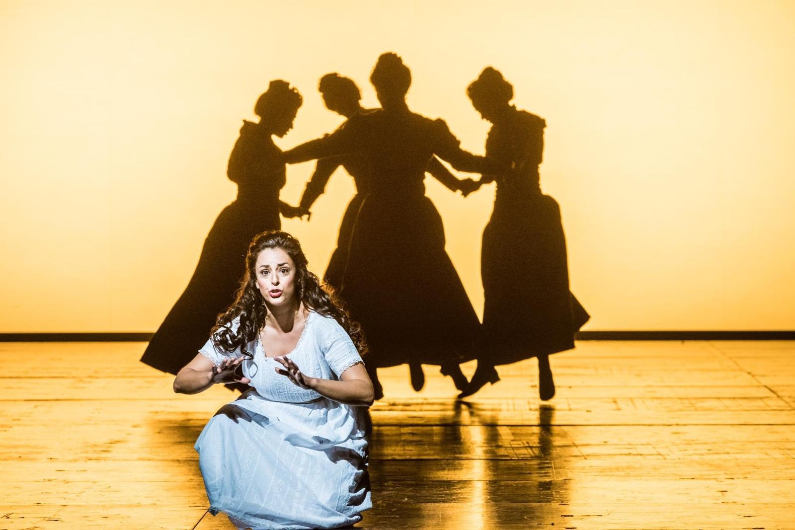 Hila Fahima in the title role of Lucia di Lammermoor, Tel Aviv 2024 — kneeling in a pale blue dress before dancing shadows, photo by Ofer Rosner