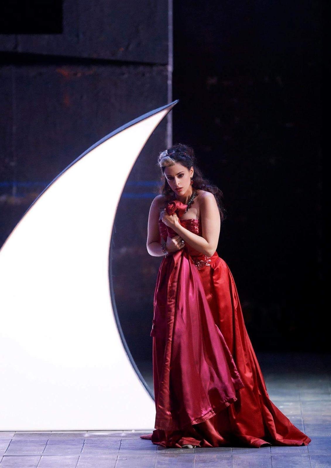 Hila Fahima as the Queen of the Night in Die Zauberflöte, Vienna State Opera 2019 — in a red satin gown beside a crescent moon, photo by Alexander Pöhn